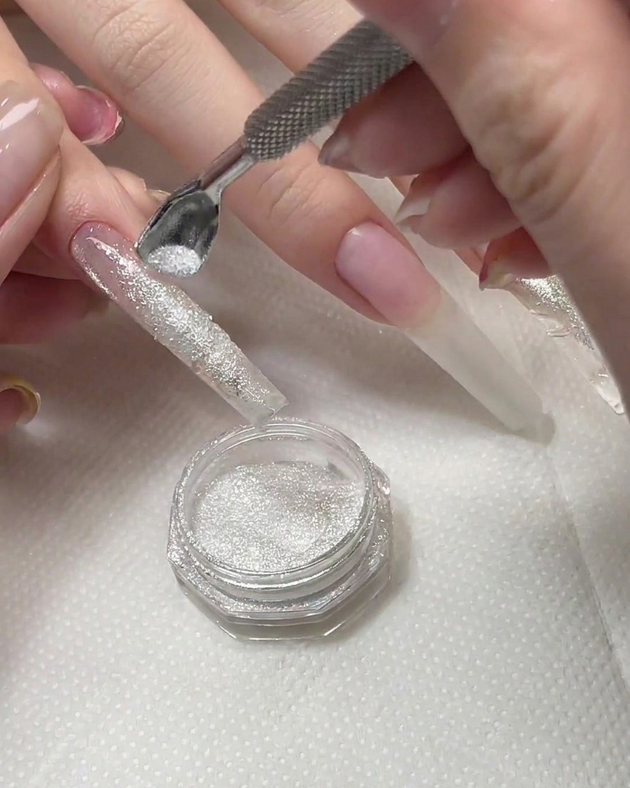 Une brosse éliminant lexcédent de poudre de diamant de la surface dun ongle catalysé.