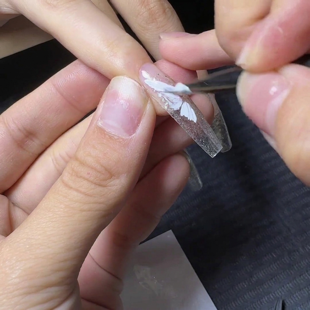 Un pinceau de détail remplissant la section inférieure du motif de laile de papillon en gel blanc.