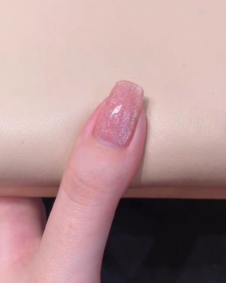 Un ongle manucuré montrant des particules magnétiques dispersées après avoir ajusté laimant cylindrique du côté gauche.