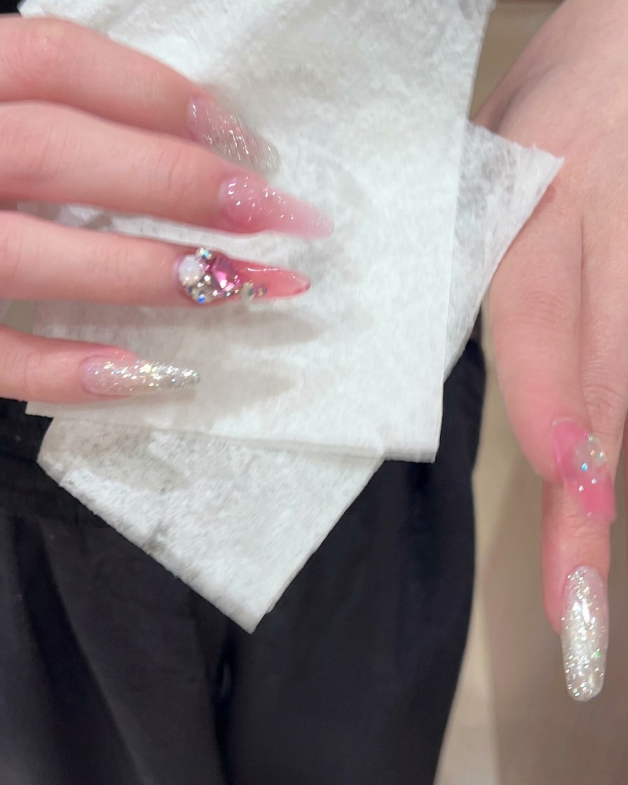 Un coton nettoyant délicatement la surface des ongles en acrylique préparés et décorés.