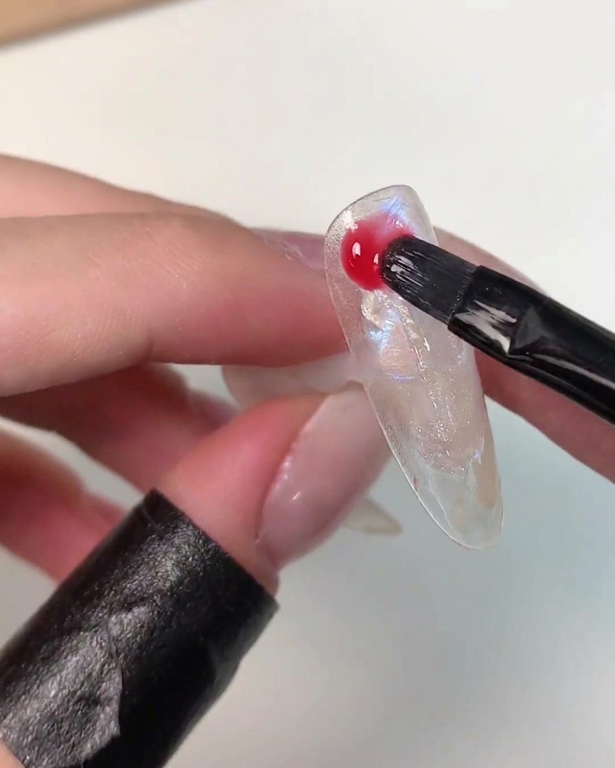 Un pinceau appliquant de manière aléatoire le gel de couleur Eiko Esaka vibrant sur la surface du nail art.