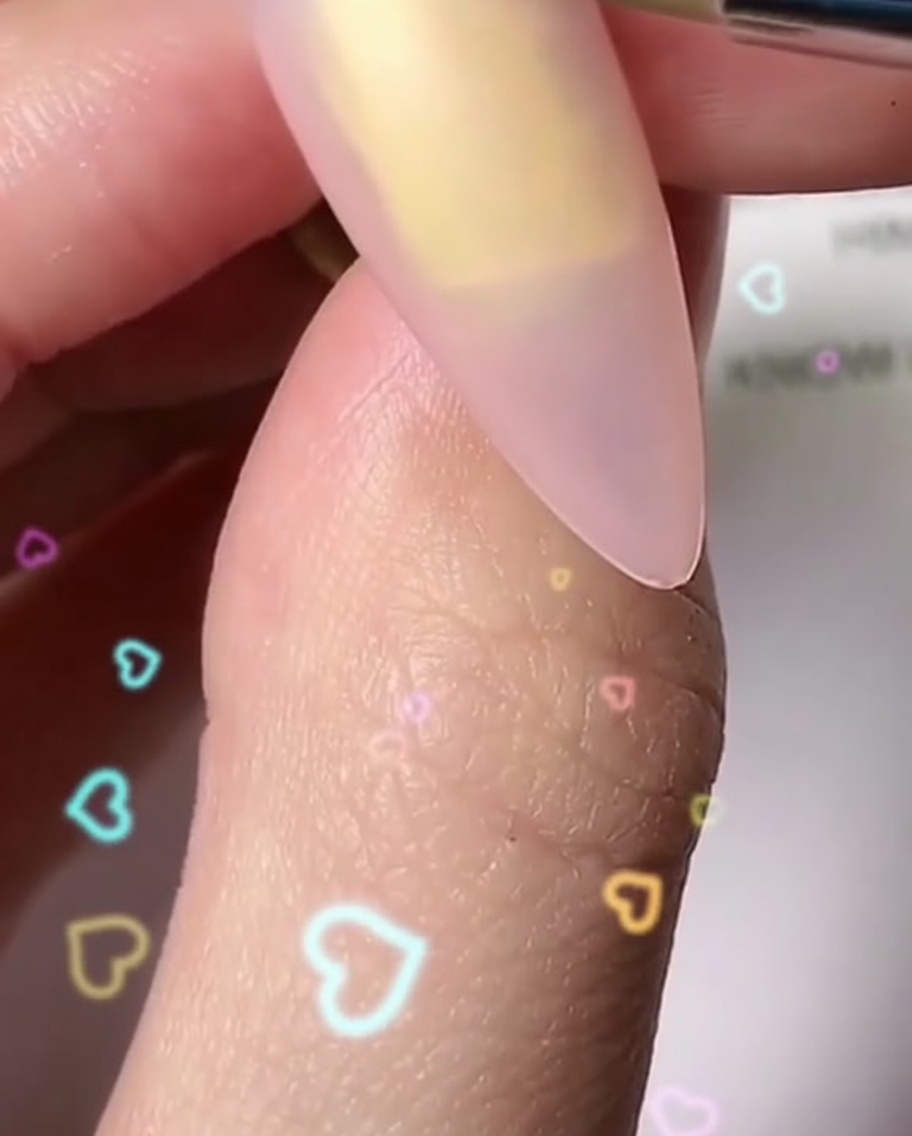 Un pinceau fin peignant des pétales blancs arrondis individuels pour former une forme de fleur sur un ongle.