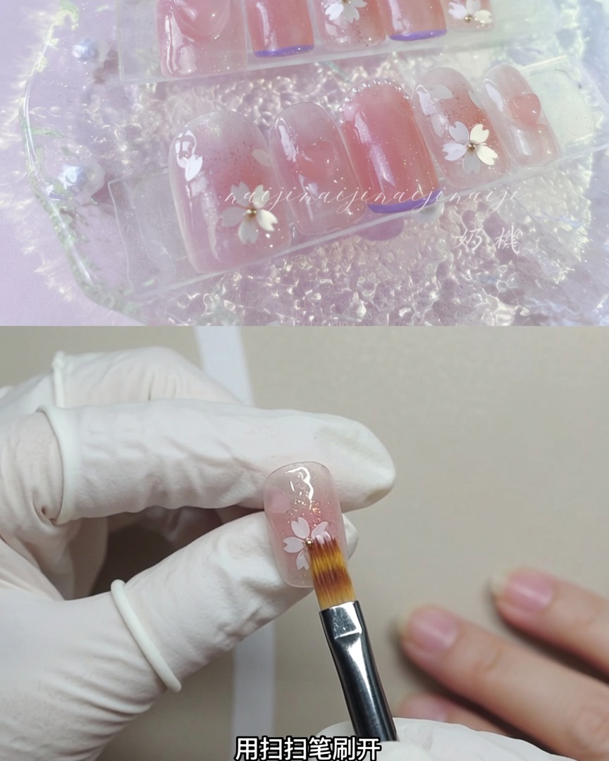 Une main gantée tenant un pinceau à poudre doux, balayant légèrement un ongle décoré pour diffuser les particules scintillantes.