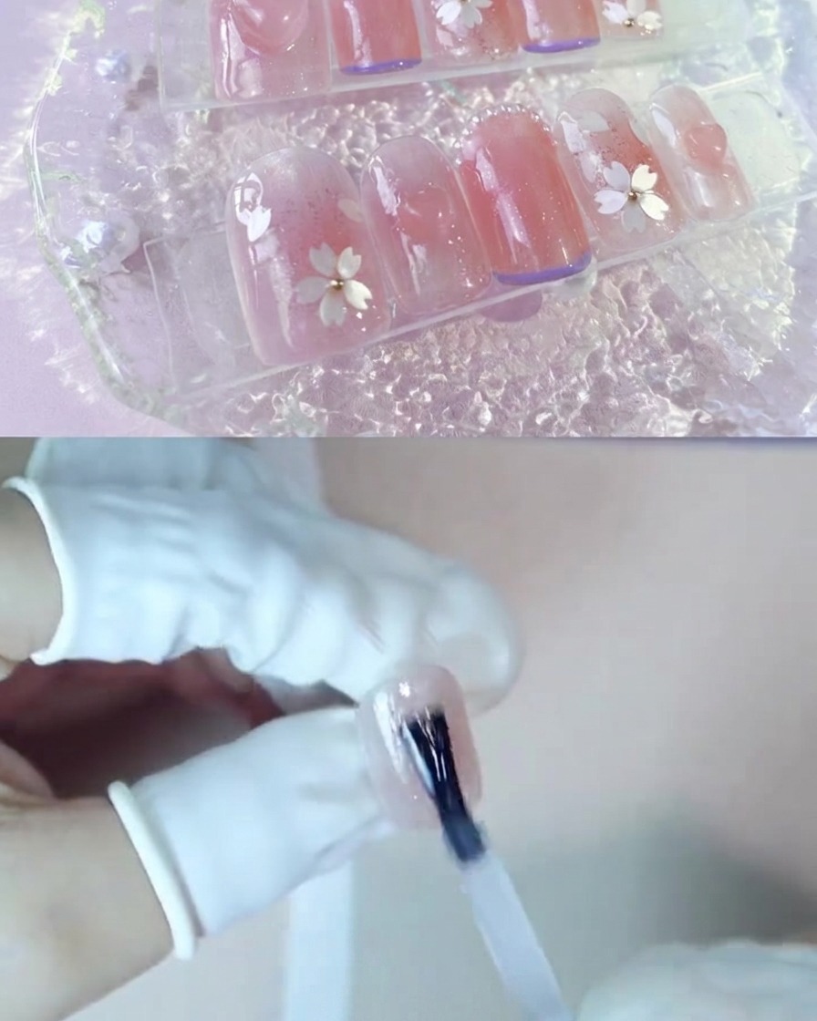 Une main appliquant une couche de gel de renforcement transparent sur un ongle rose blush.