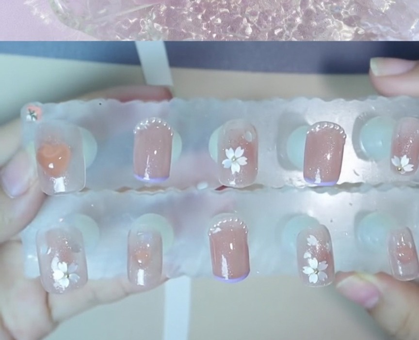 Gros plan dune petite bille en acier positionnée au centre dun motif floral sur un ongle.