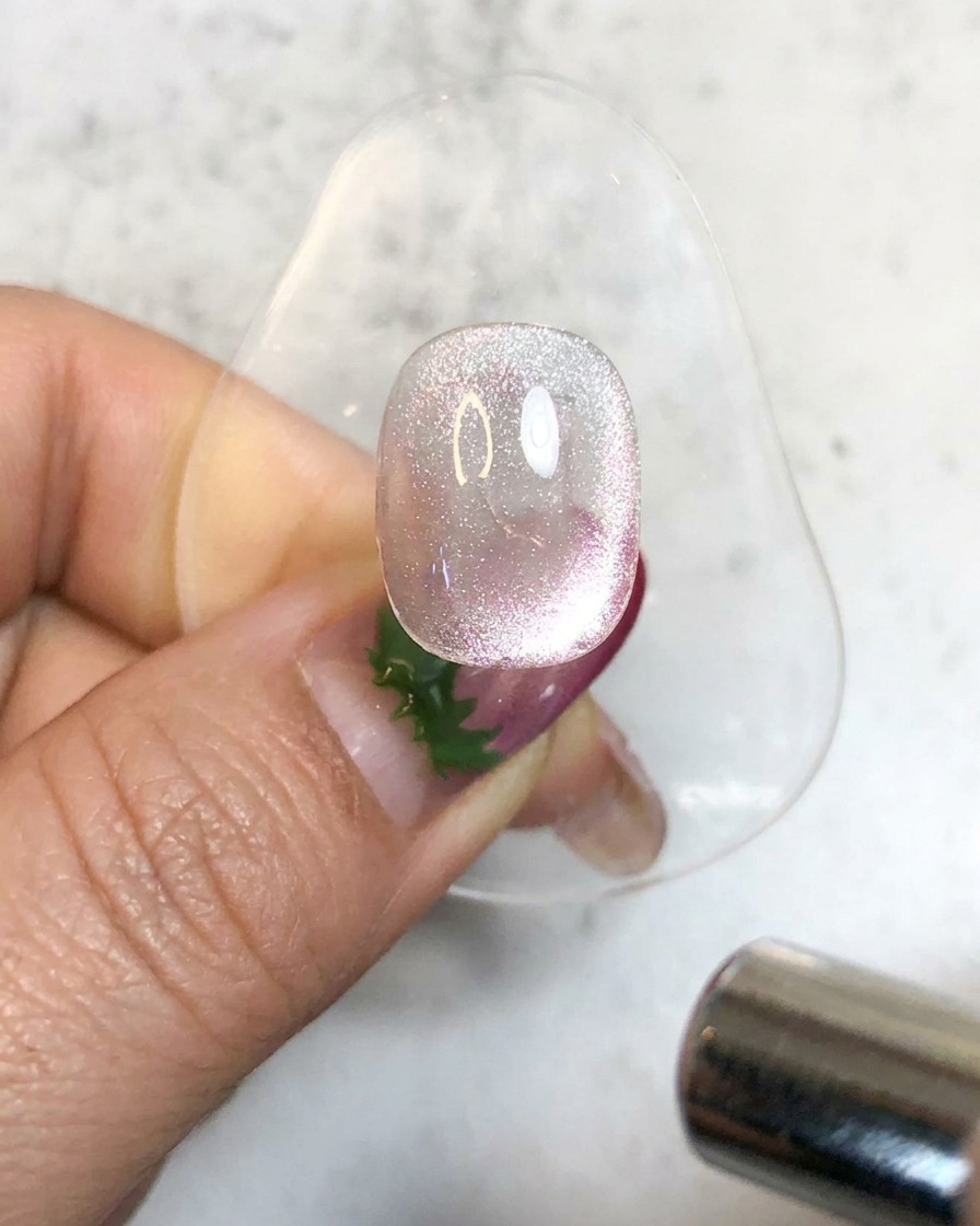 Une lampe UV portable illuminant un ongle en gel magnétique brillant sur un support pour le catalyser.