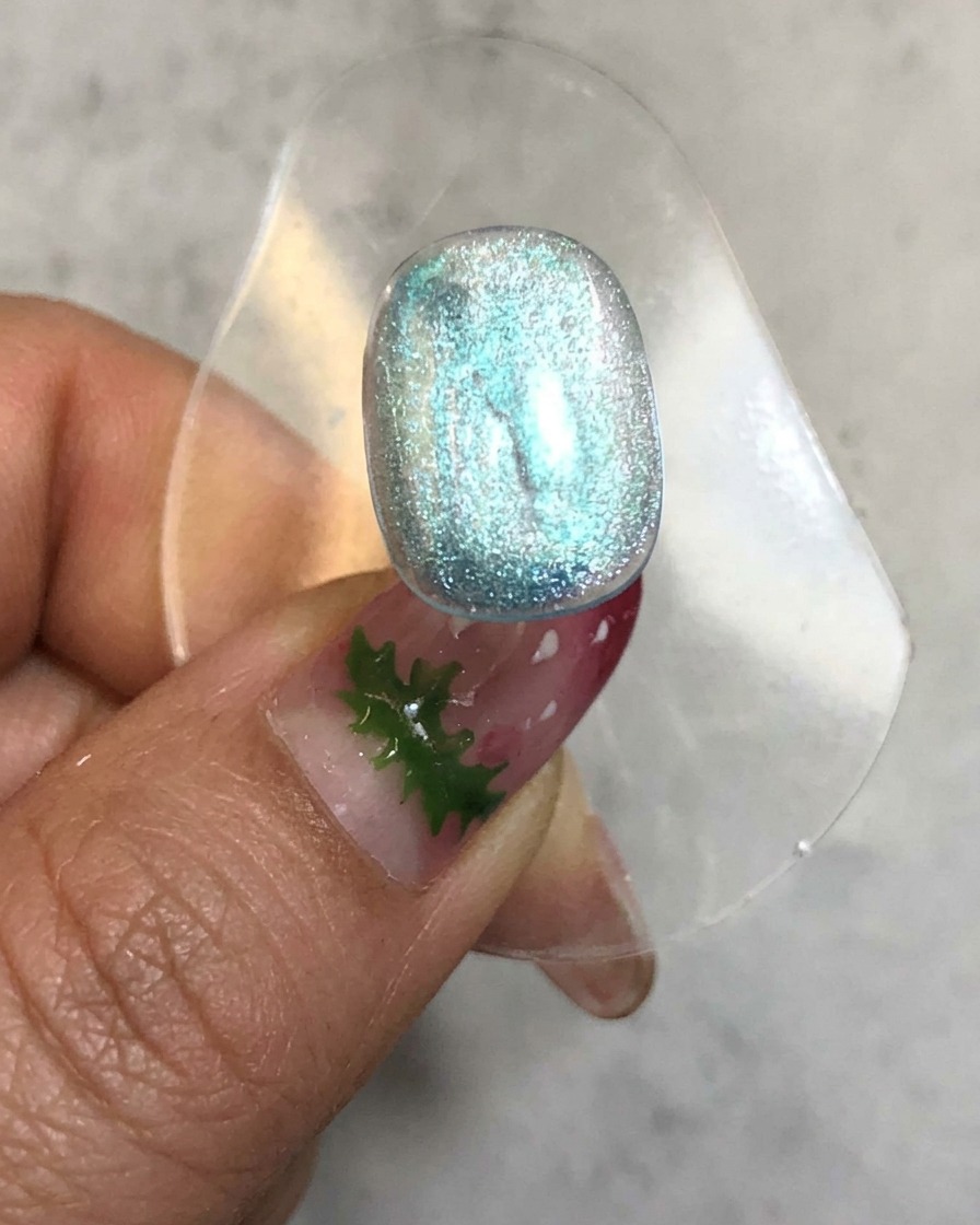 Un ongle placé à lintérieur dune lampe de catalysation avec une lumière incandescente émettant autour de la surface en gel bleu translucide.