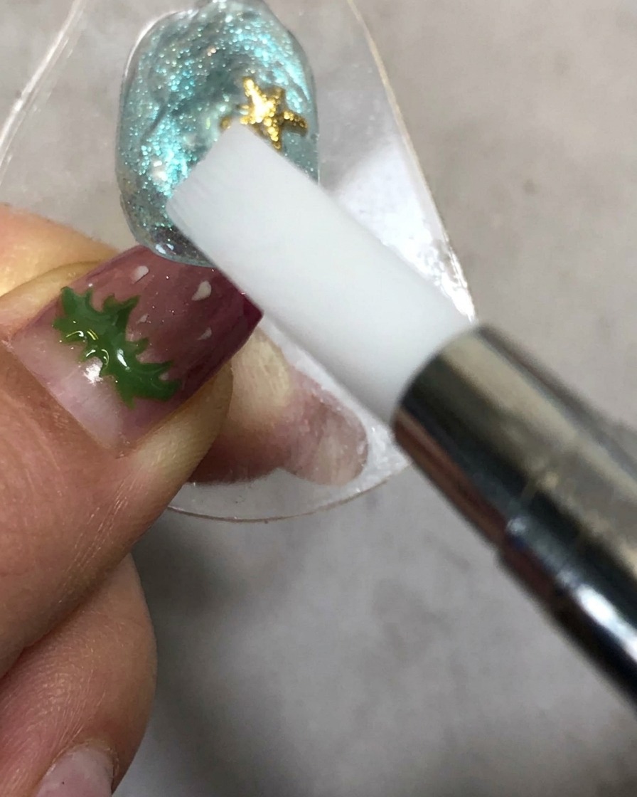Une main tenant un outil de modelage en silicone près dun ongle sous une lampe de catalysation.