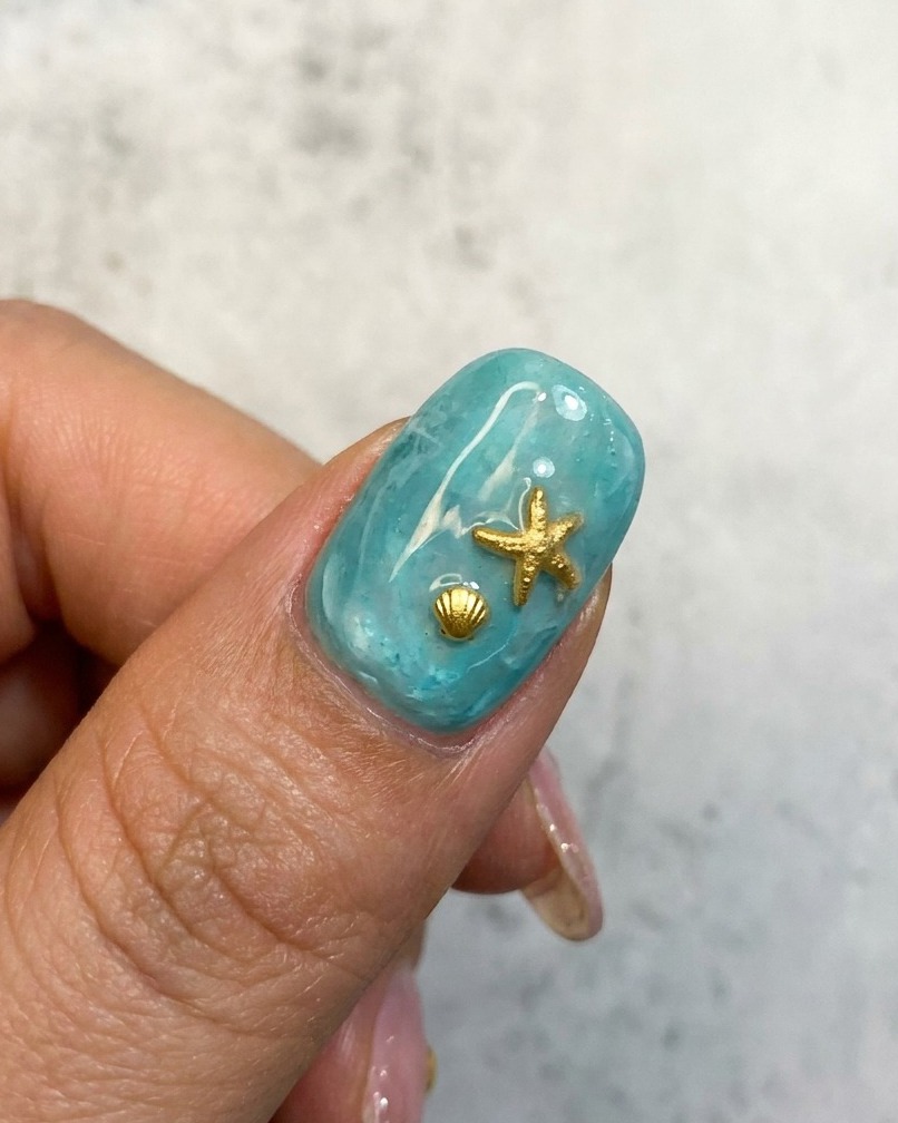 Un gros plan dun design dongle océanique bleu avec une étoile de mer dorée et un embellissement de coquillage.