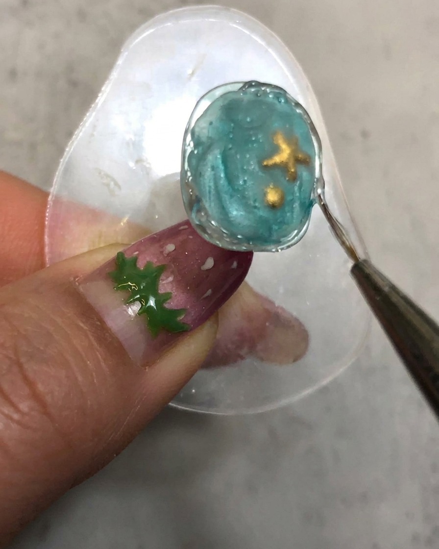 Un pinceau de détail traçant le long de la bordure texturée en gel de modelage catalysée de longle.
