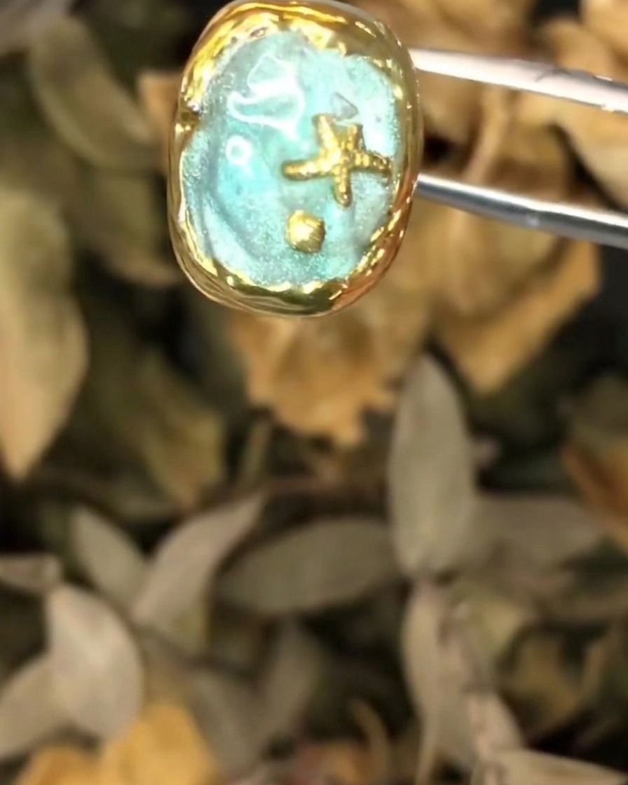 Une paire de pinces tenant la pièce dart dongle océanique texturée pendant lapplication de la couche finale.
