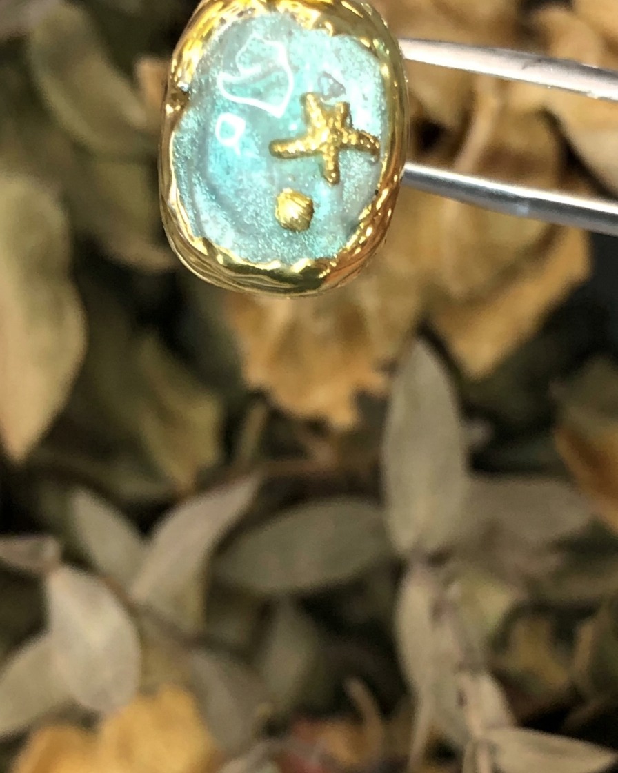 Une vue en gros plan de la pièce dongle de style Atlantis finie et tenue par des pinces.