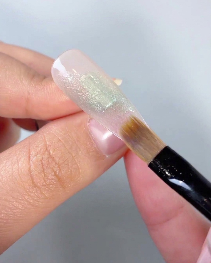 Gros plan dun pinceau souple estompant les bords dun bloc de couleur en gel vert sur une capsule dongle.