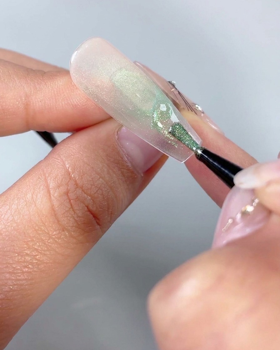 Un pinceau fin pour nail art dessinant de petites formes triangulaires incurvées près de la base inférieure dun design dongle papillon.