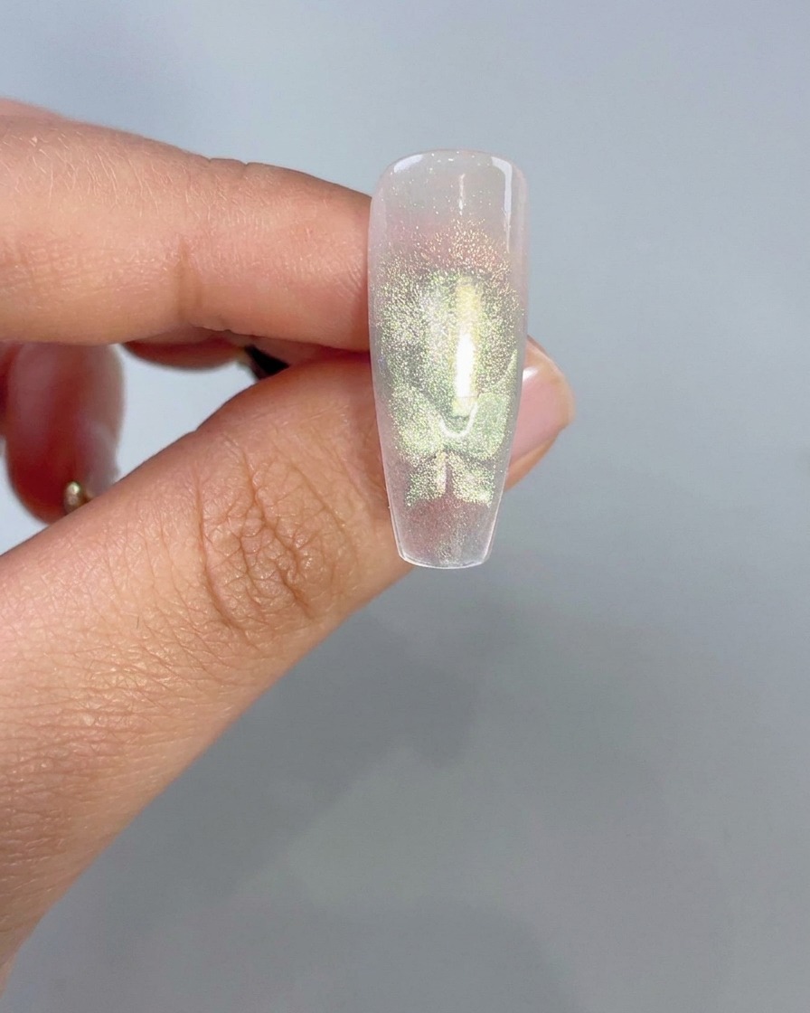 Gros plan dune capsule dongle transparente affichant des formes dailes de papillon œil-de-chat vertes lumineuses après activation magnétique.