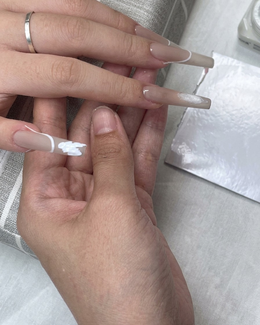 Un autocollant guide de French tip placé sur longle tandis que du gel blanc remplit la zone de la لب.