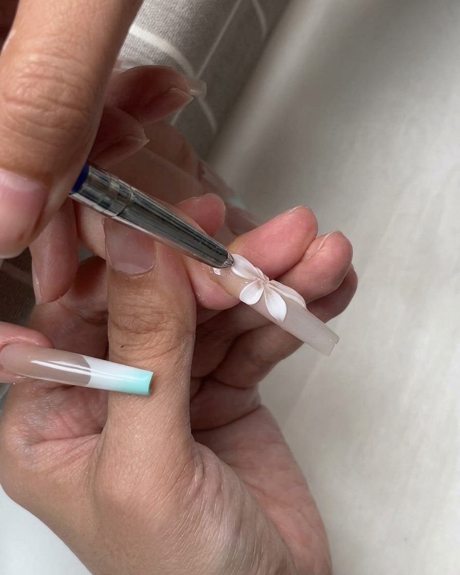 Un outil en silicone façonnant plusieurs pétales 3D blancs disposés en une fleur complète sur un ongle.