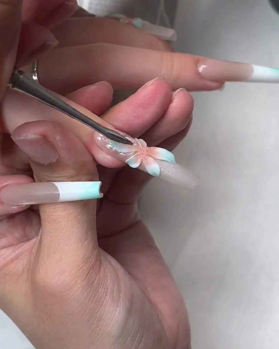 Un outil pressant une couche de gel de construction souple transparent sur la fleur peinte pour créer des pétales translucides plus grands.