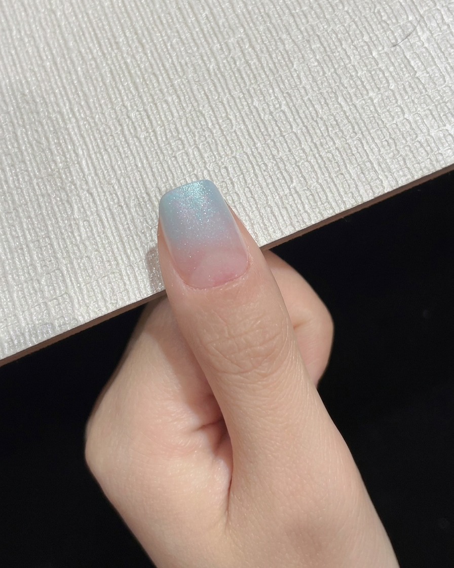 Un ongle ombré à dégradé bleu terminé présenté comme un cliché de progression intermédiaire.