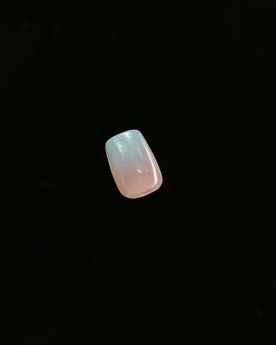 Gros plan dun seul ongle fini montrant un effet ombré en dégradé sur un fond sombre.