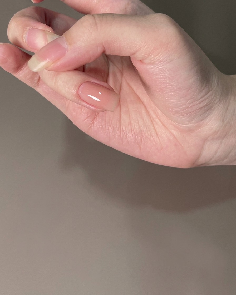 Un ongle revêtu dune base nude catalysée sous un éclairage.