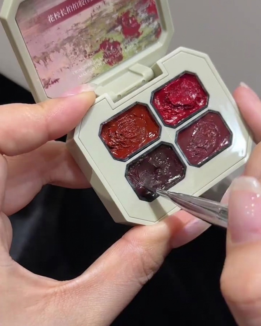 Gros plan dun pinceau fin de nail art trempant dans un compartiment spécifique dune palette de gel rose à plusieurs compartiments.
