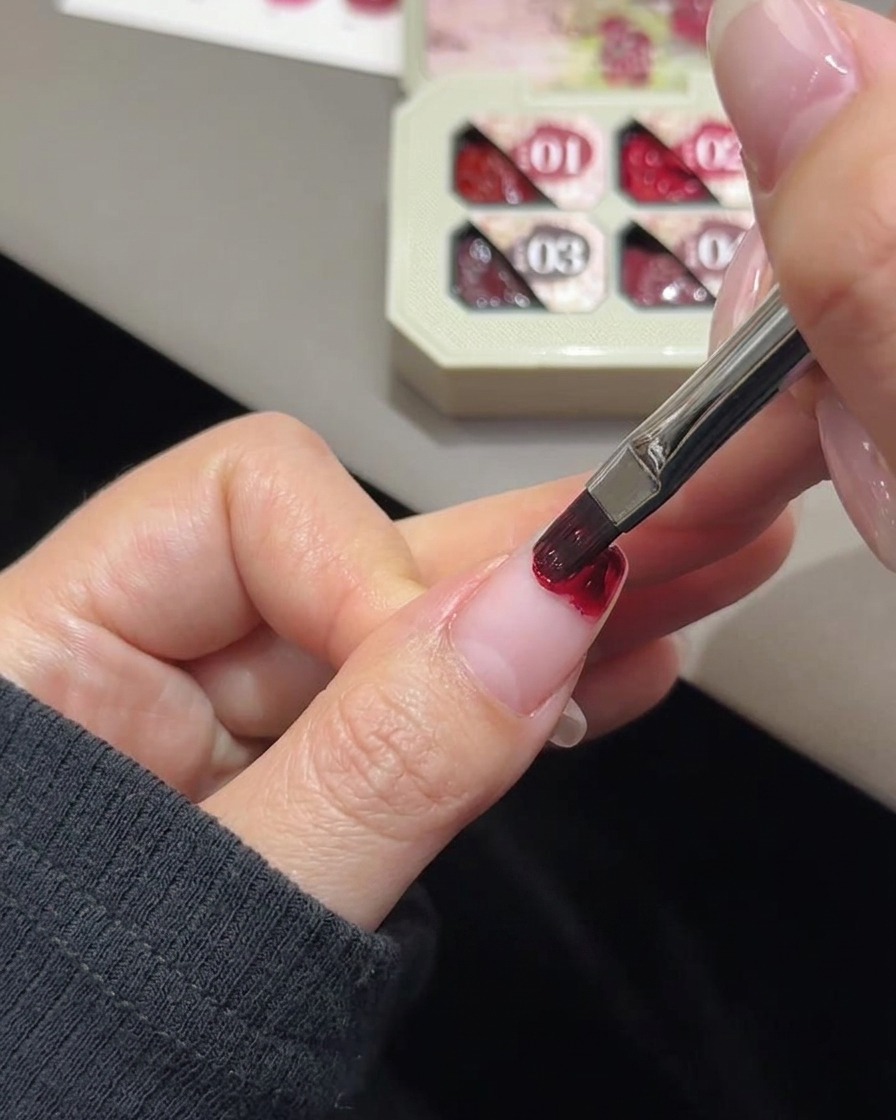 Un petit morceau déponge de maquillage blanche estompant la couleur du gel rose sur le bout dun ongle.