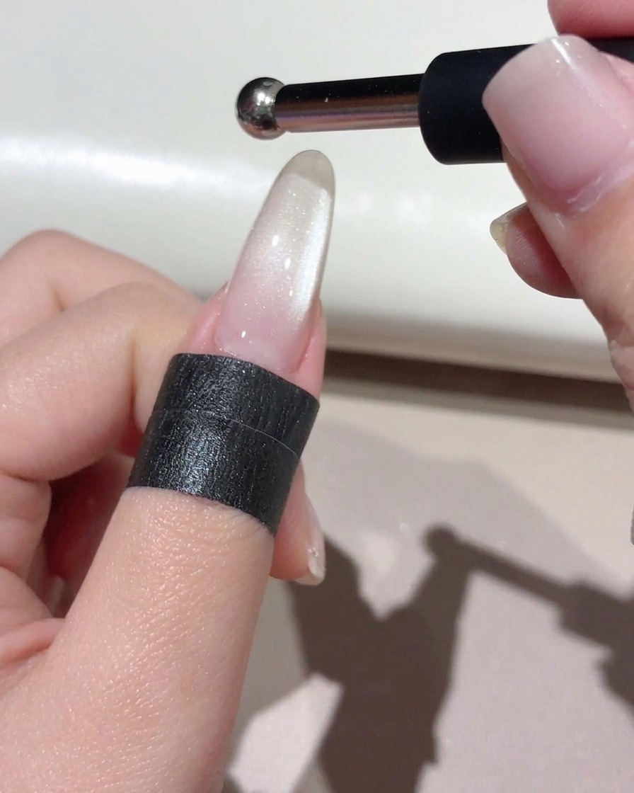 Un petit aimant à pointe sphérique tenu au-dessus de longle pour façonner un reflet de perle de verre concentré.