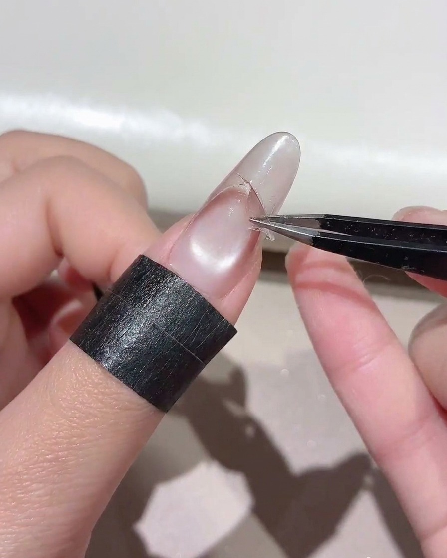 Des pinces tirant un autocollant incurvé dun ongle pour exposer une ligne de dégradé nette.