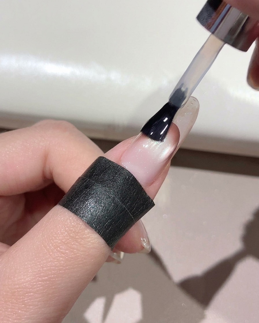 Un pinceau appliquant un top coat transparent sur toute la surface dun ongle manucuré.