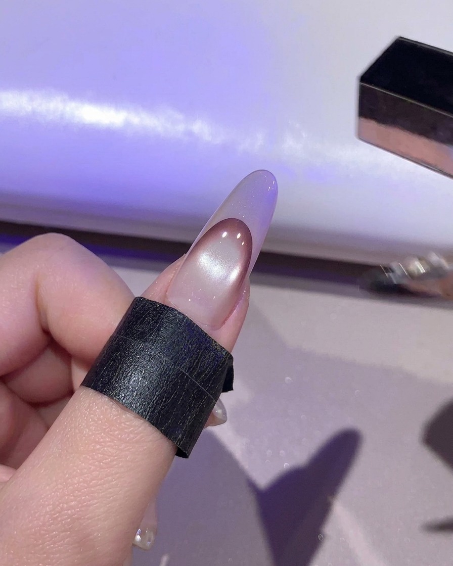 Un ongle en train de catalyser sous une lumière violette à lintérieur dune lampe UV LED.