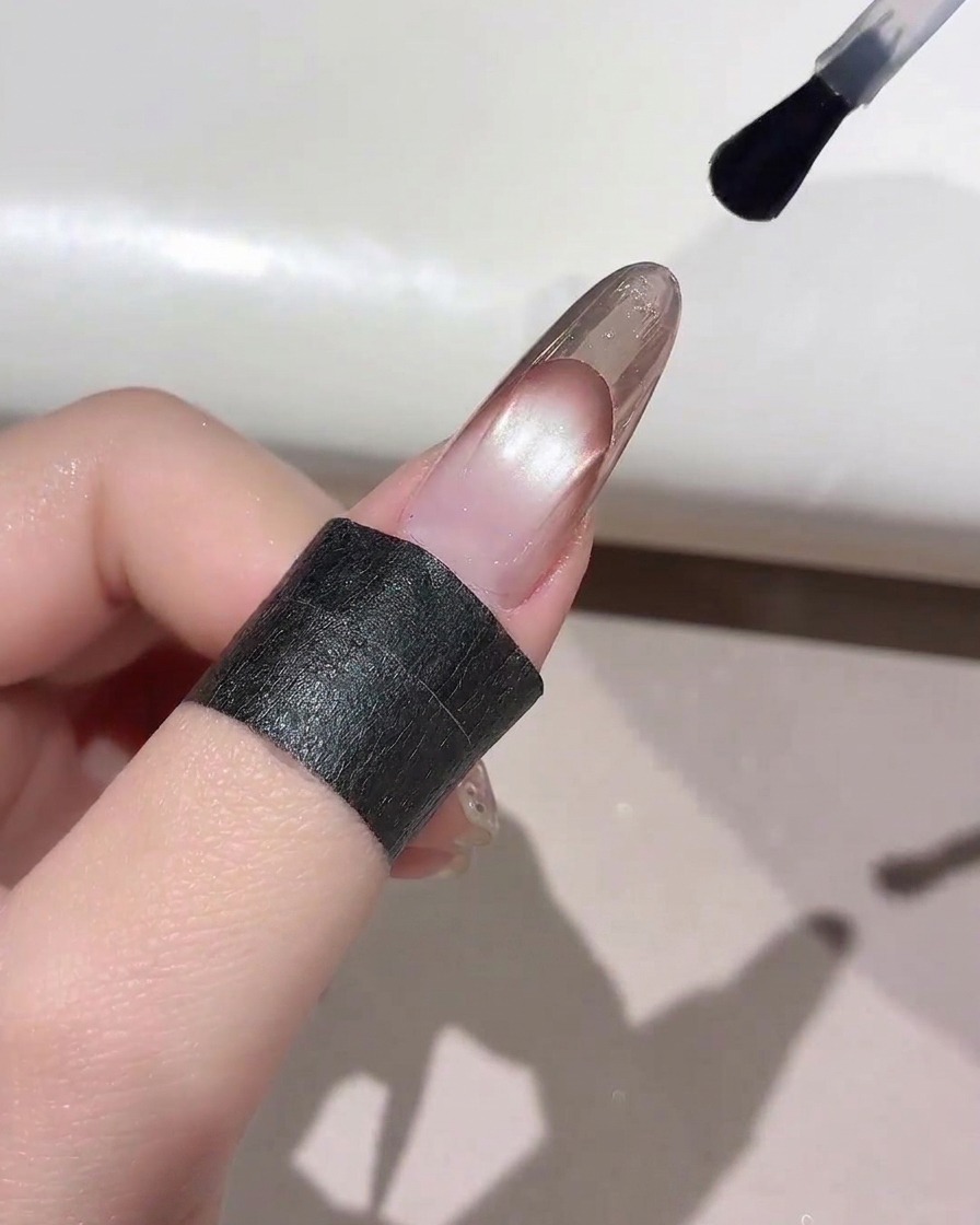Un pinceau à ongle appliquant un top coat transparent sur le bout dune French manucure finie.