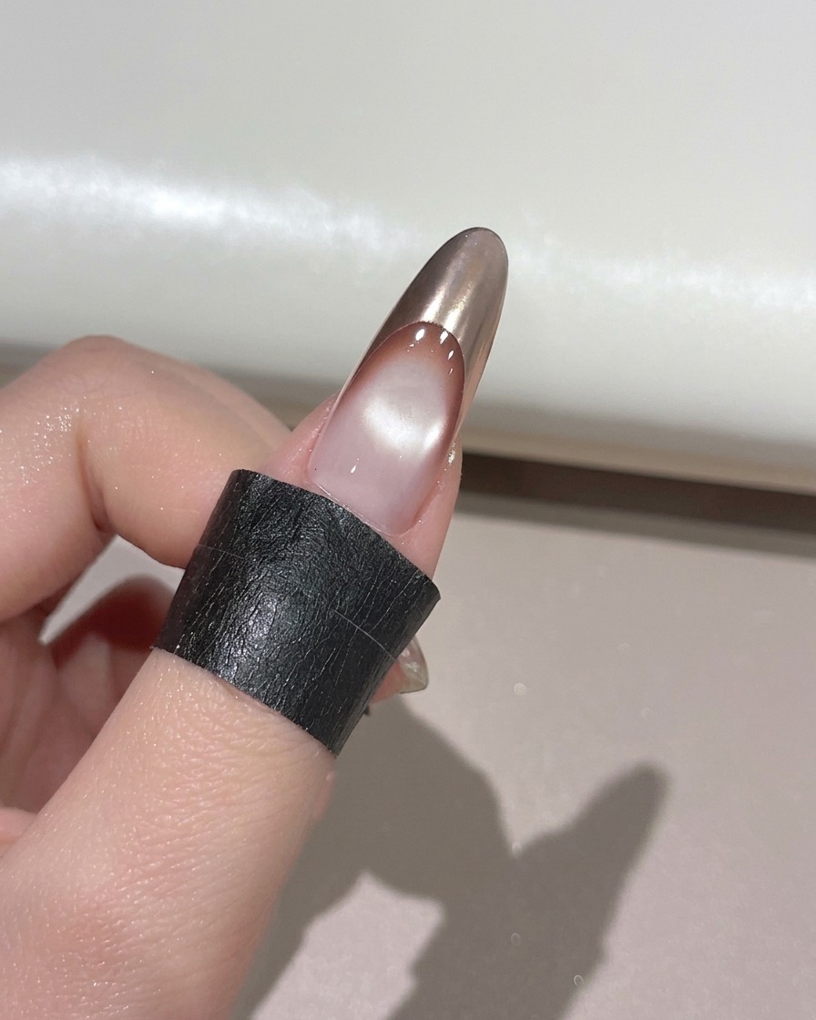 Un doigt avec une pointe French chrome or reposant à lintérieur dune lampe à ongles UV pour la catalyse.