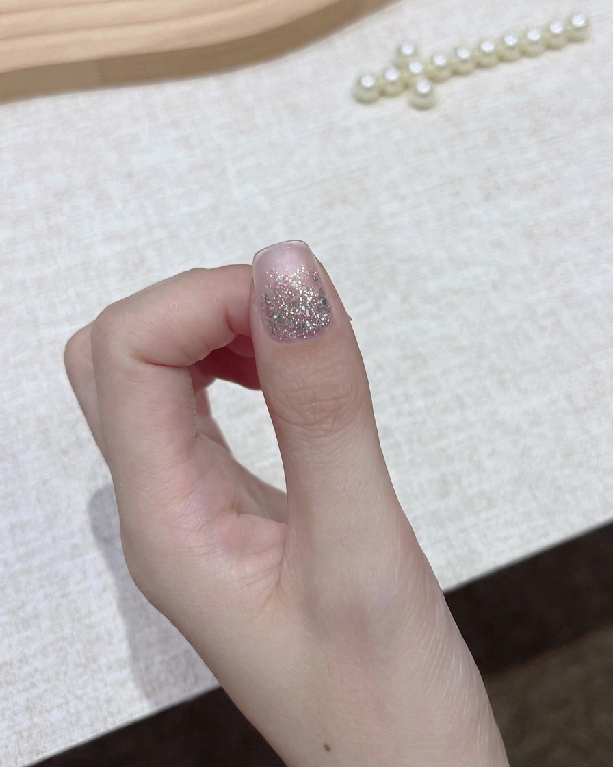 Une main tenant un flacon de vernis gel sombre avec le bouchon retiré, se préparant pour létape dapplication.