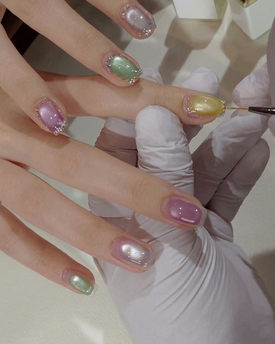Vue rapprochée de petites paillettes papillon colorées posées sur la surface dun ongle décoré à laide dun outil fin.