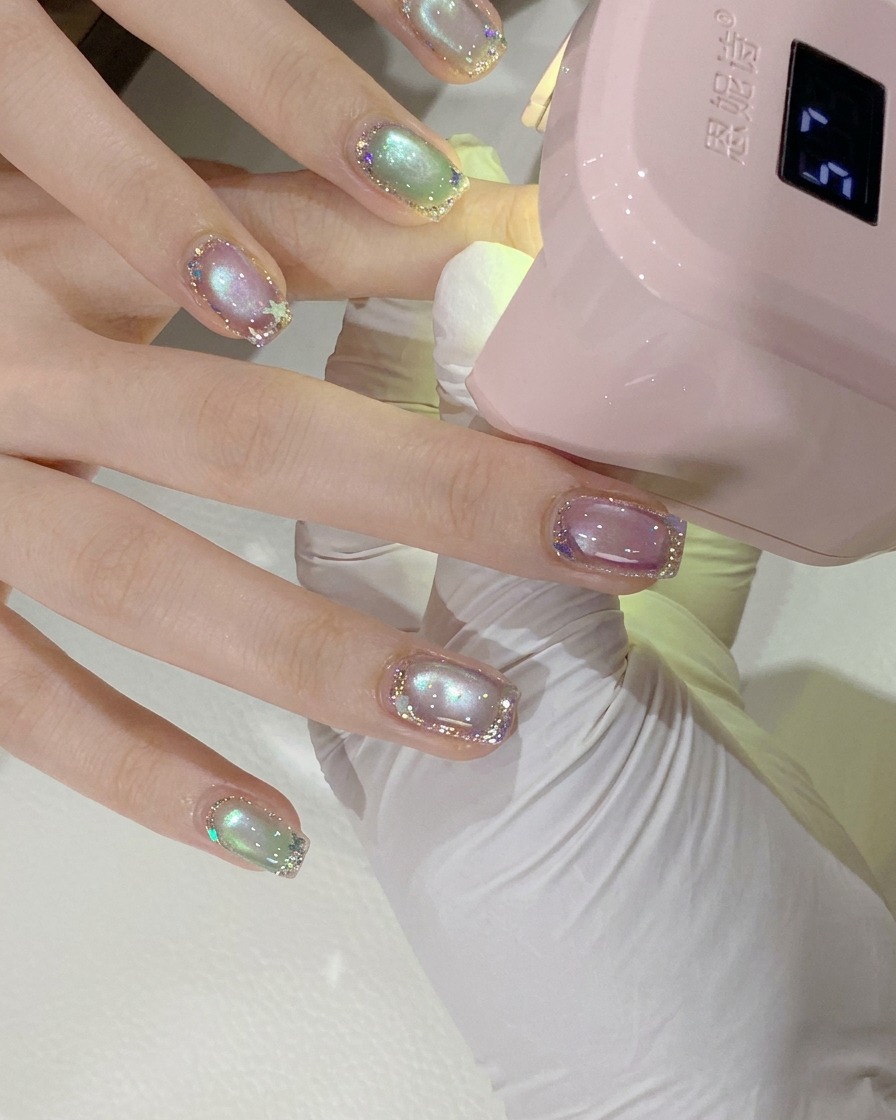 Gros plan de la main dune cliente positionnée sous une mini lampe à ongles UV/LED rose pour la catalysation.