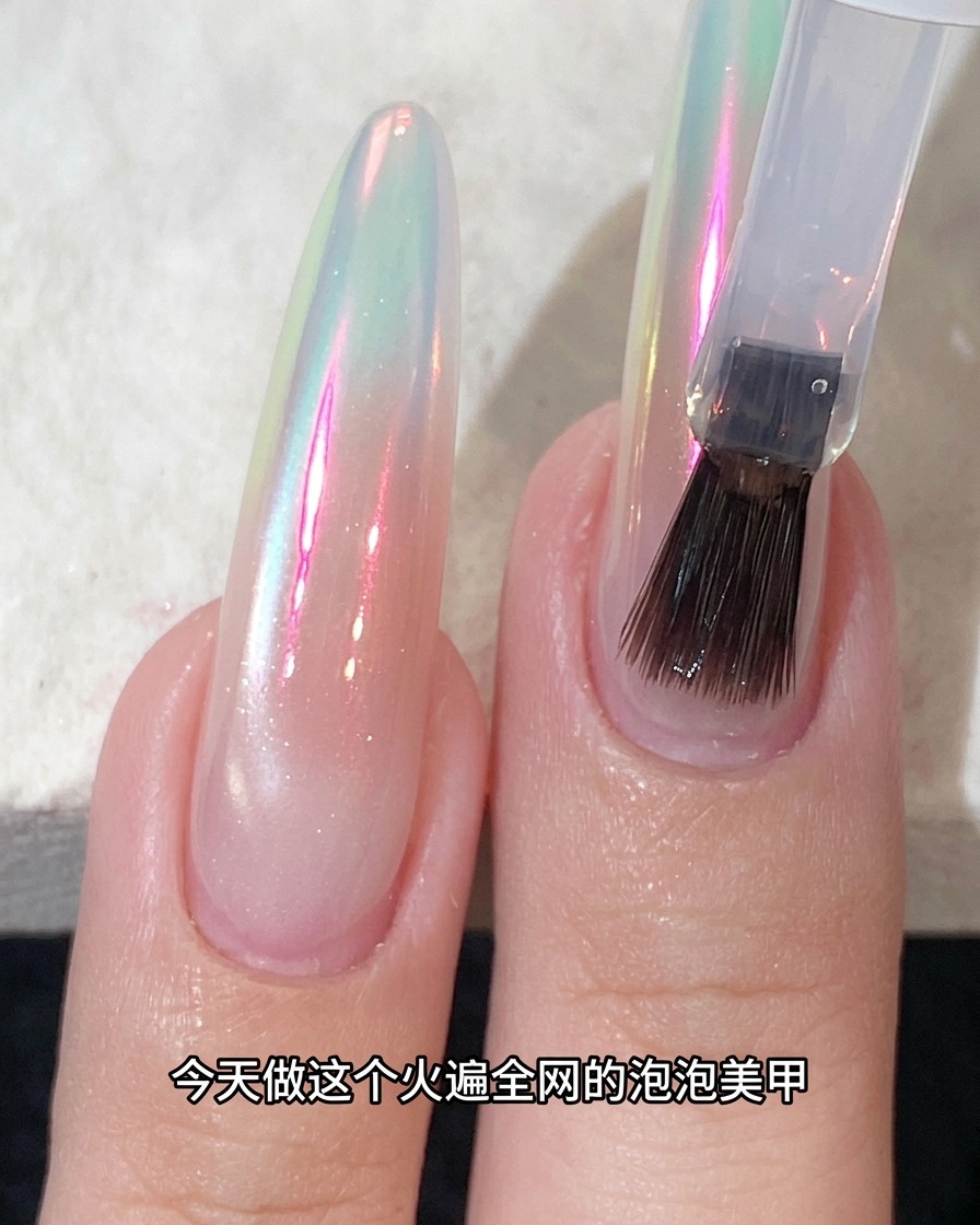 Un pinceau appliquant un top coat sur un ongle à finition chrome scintillante.