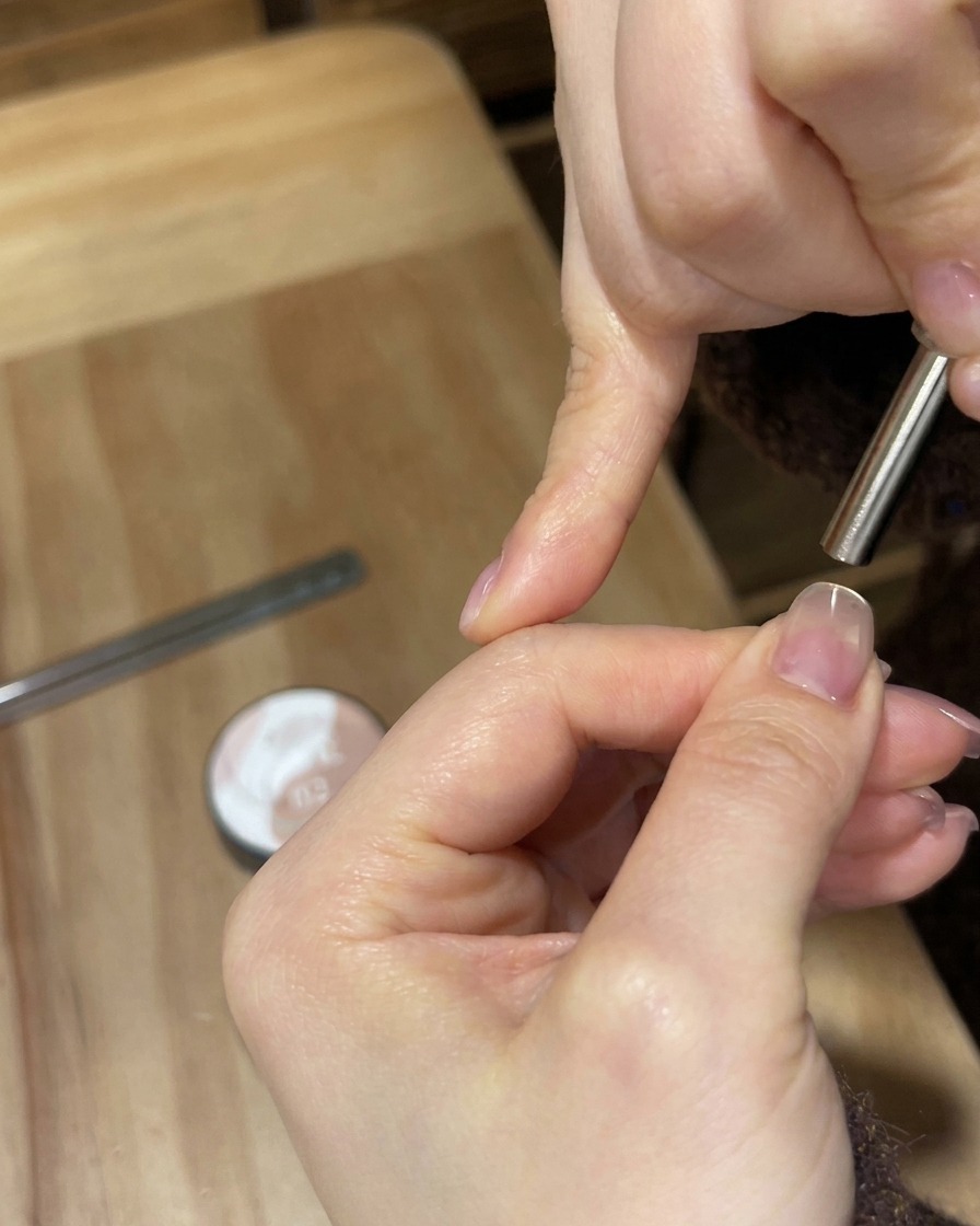 Une lampe UV/LED blanche portable brillant de mille feux sur un ongle pour catalyser le revêtement en gel.