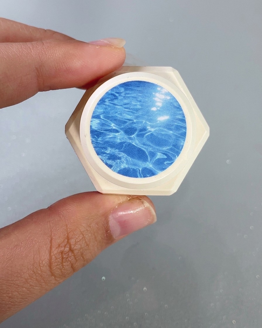 Gros plan dun pinceau à ongles appliquant un gel vitrail bleu transparent sur le bout de longle.