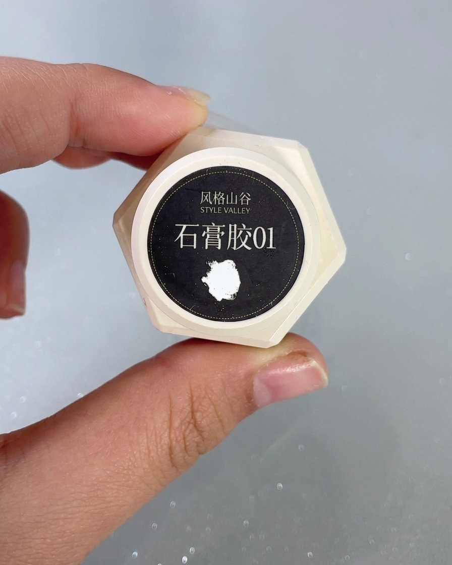 Un pinceau fin pour nail art détaillant un motif de vagues blanches en relief à laide de gel plâtre sur un ongle.