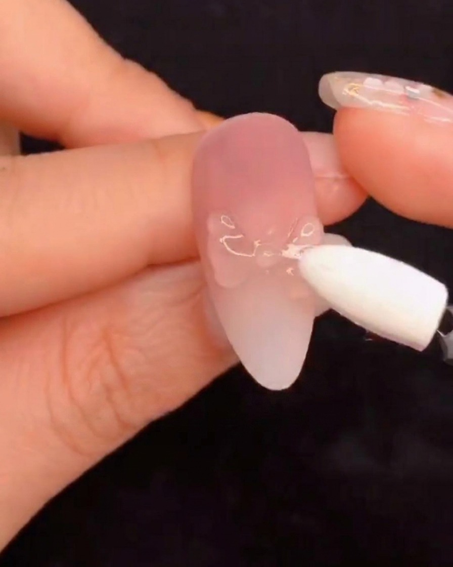 Un applicateur en mousse silicone frottant de la poudre de pigment aurora sur un design dongle sculpté.