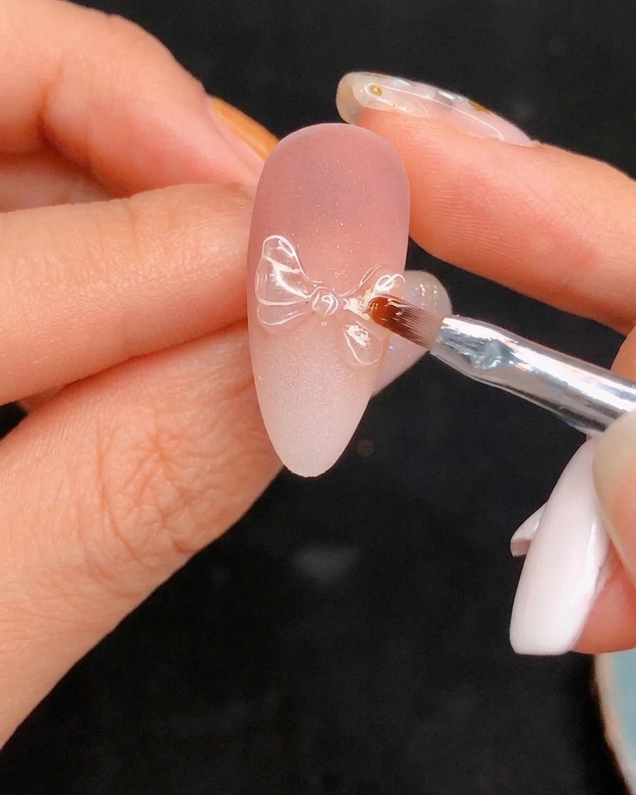 Application du top coat brillant final sur le nail art détaillé.