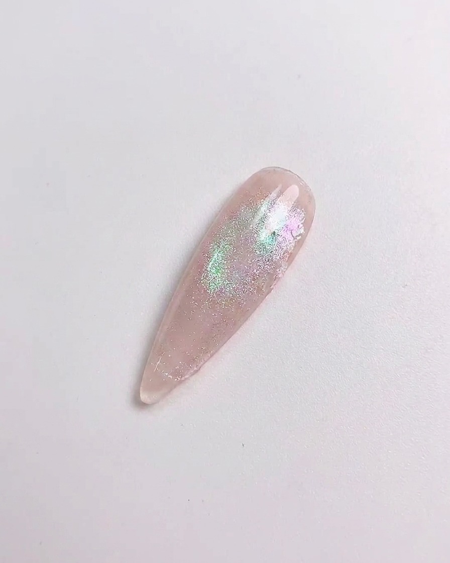 Un outil en silicone frottant de la poudre aurore sur la surface dun ongle catalysé.