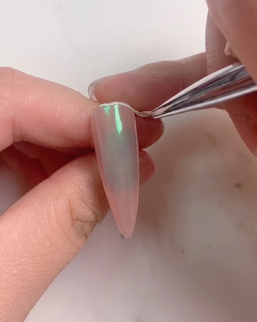 Une brosse douce balayant lexcédent de poudre dun ongle aurore terminé.