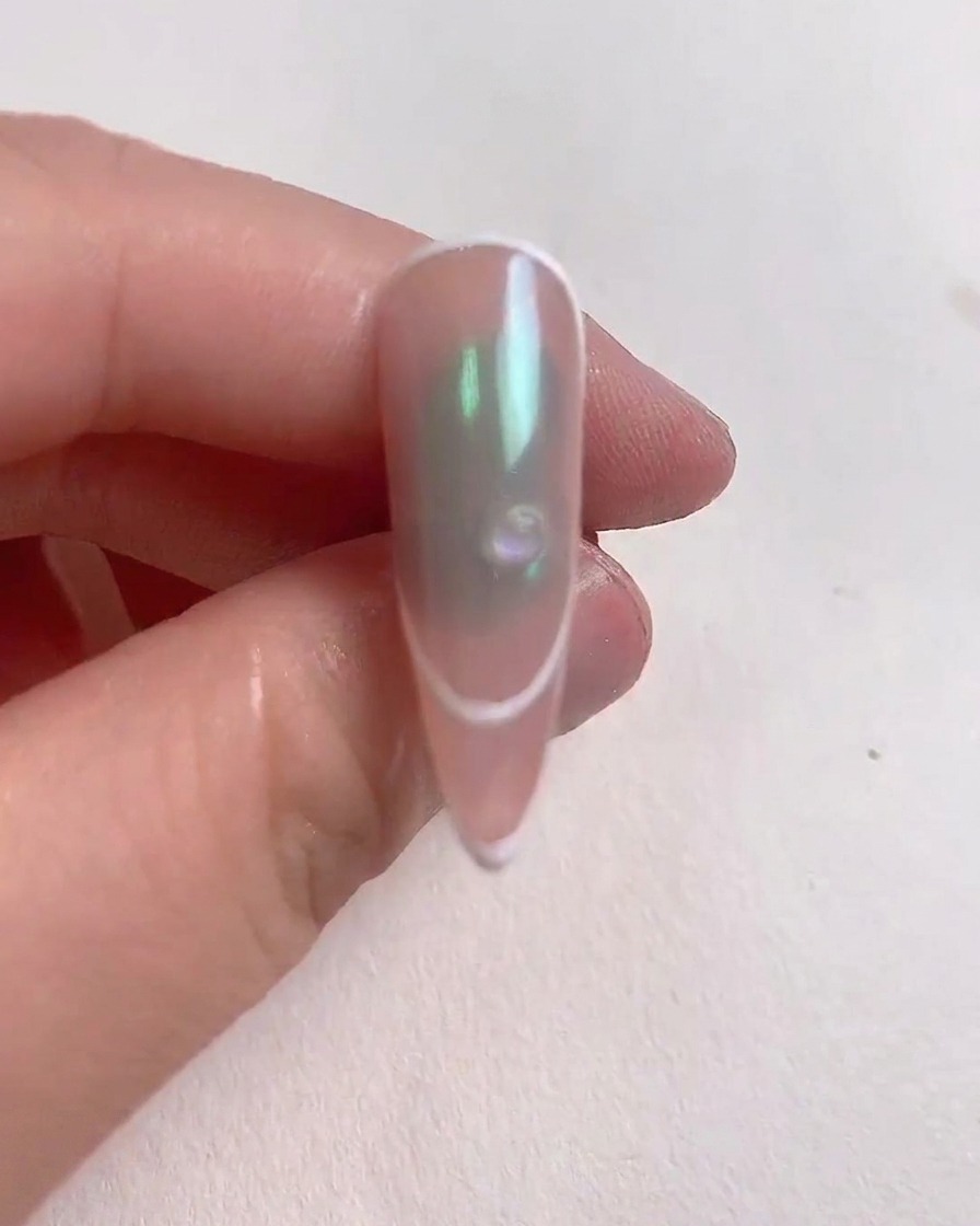 Une petite goutte transparente de gel de renfort placée au centre dun ongle décoré.