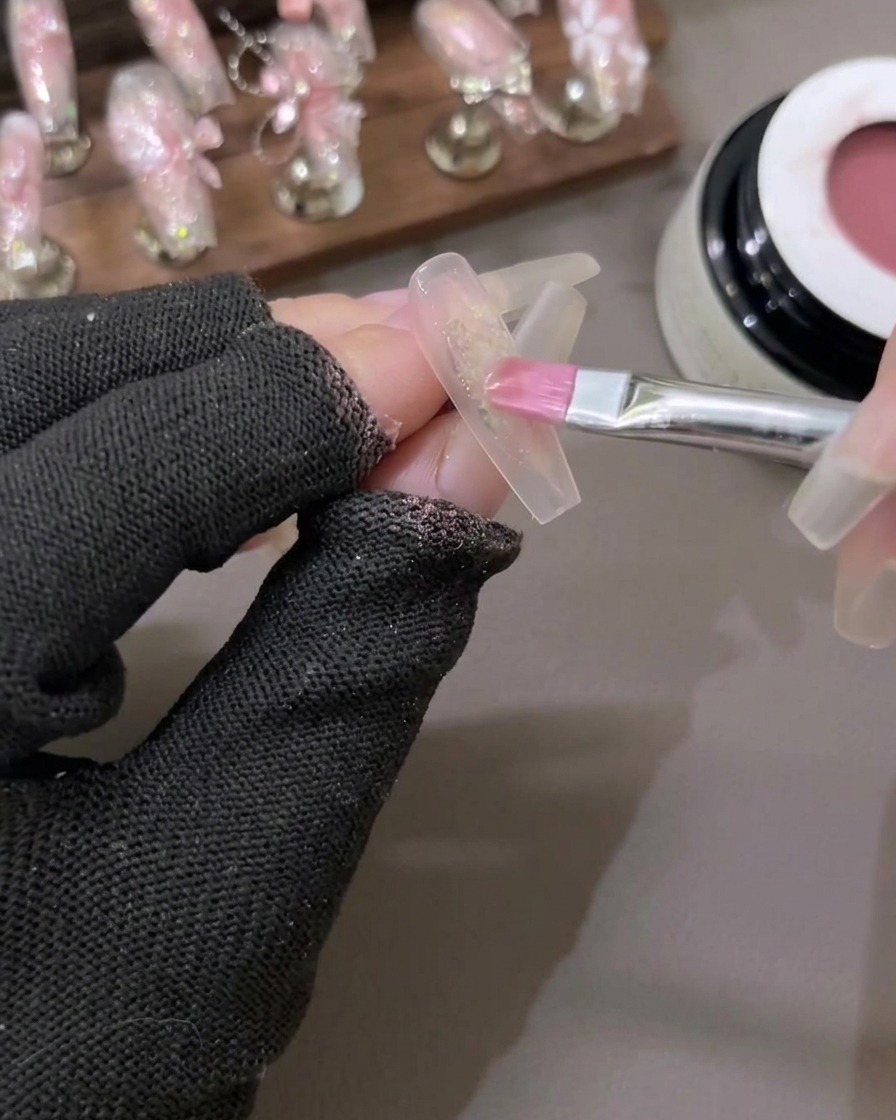 Un pinceau estompant délicatement une couleur de gel rouge diaphane au centre de longle pour créer un effet de dégradé.
