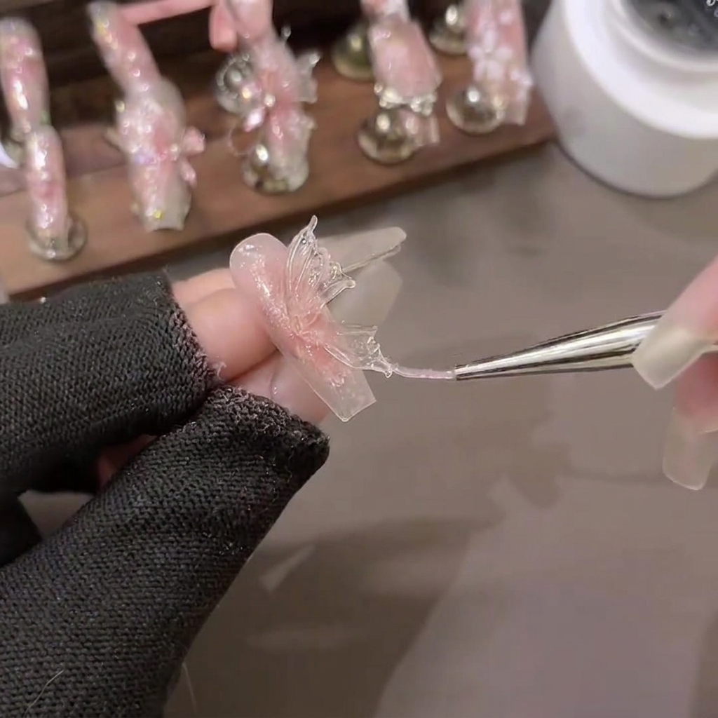 Un pinceau de modelage façonnant un triangle de gel dextension souple PVC pour former des ailes de papillon détaillées sur du papier de support.
