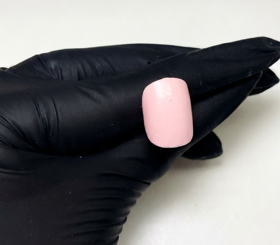 Gros plan dun ongle rose préparé avec un petit point de builder gel rose placé en haut au centre.