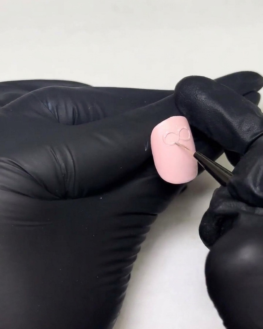 Mains gantées ajoutant une couche plus épaisse de builder gel sur les boucles existantes dun motif de nœud 3D sur un ongle.