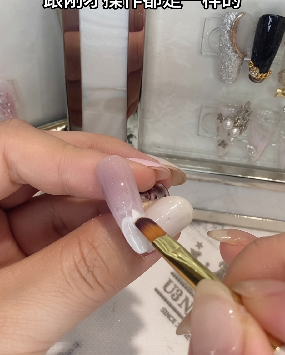 Un pinceau estompant du gel blanc sur la moitié inférieure dun ongle ombré.